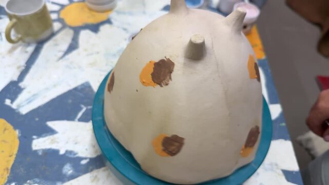 An artisan hand-paints a clay vase with colorful glazes using a brush. The creative pottery process highlights craftsmanship, tradition, and the beauty of handmade ceramic art