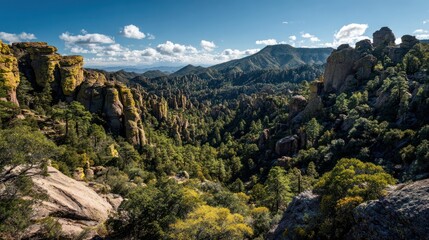 Naklejka premium Panoramic view of rugged mountains, dense forests, and scattered clouds under a vibrant blue sky