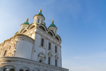 Obraz premium Assumption Cathedral at Astrakhan Kremlin with elegant white architecture with turquoise domes and golden crosses during soft evening light, Astrakhan, Russia. 