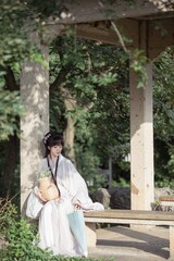 Young Asian woman in traditional attire relaxing outdoors.