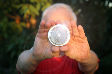 Classic shining compass in hands of man on natural background