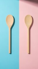 Two wooden spoons on a split blue and pink background