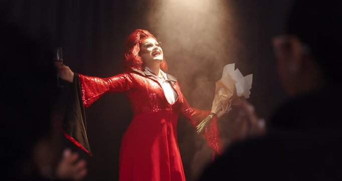 Applause, champagne and stage with drag performer in theater for lgbt culture, nightlife and spotlight show. Identity, entertainment and winner with person and audience for celebration and pride
