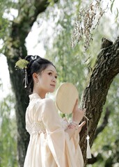 Woman holding a round mirror in a serene outdoor setting.