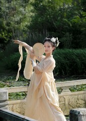 Young Asian woman in traditional dress by serene water.
