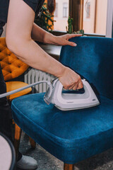 young woman using iron to steam chair in hotel
