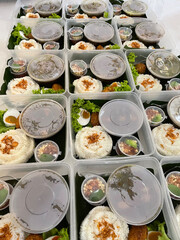 A row of white rice food packages with side dishes and vegetables in round container boxes and plastic boxes for catering, white rice catering menu in food catering business