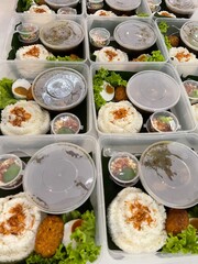 A row of white rice food packages with side dishes and vegetables in round container boxes and plastic boxes for catering, white rice catering menu in food catering business