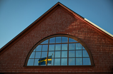 Swedish Flag Reflected in Arched Window of Brick Building