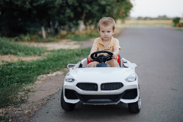 2 years boy riding electric car toy on a road