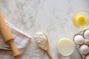 Baking ingredients arranged on a marble countertop for a homemade recipe in a cozy kitchen setting
