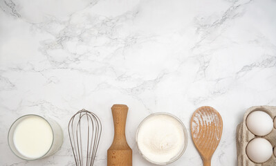 Baking essentials arranged on a marble countertop with flour, eggs, and milk for a delicious recipe...