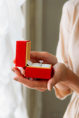 Woman holding engagement ring in red box
