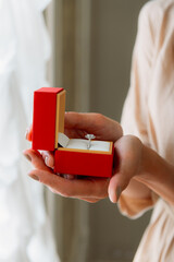 Woman holding engagement ring in red box