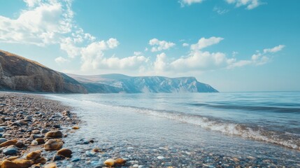 Serene view of a beach with clear blue sky and white clouds, the sea gently lapping against the shore