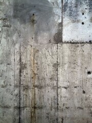 Texture of grey concrete wall with dark water and oil marks running vertically down
