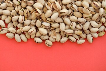 Tasty unpeeled pistachios on bright red background, top view flat lay background pattern