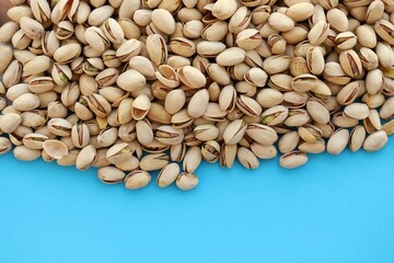 Tasty unpeeled pistachios on bright blue background, top view flat lay background pattern
