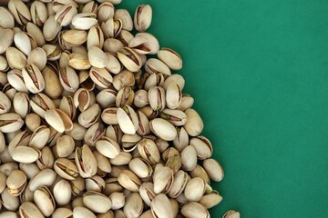 Tasty unpeeled pistachios on bright green background, top view flat lay background pattern