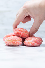 Hand taking a liberal from a stack on a light background, highlighting the details of the sugary...