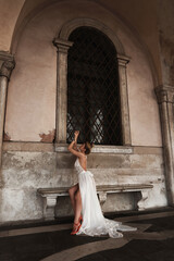 Woman in Flowing White Dress Posing in Historic Archway