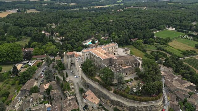 Aerial drone view of Grignan Castle surrounded by lush greenery and historic village in Provence, France &ndash; medieval fortress with scenic landscape and vibrant natural surroundings