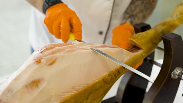 Close-up of a chef slicing jamon ham at an upscale food event. Traditional Spanish delicacy served fresh for guests at a reception, buffet, or gourmet tasting table