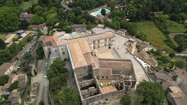 Aerial drone view of Grignan Castle surrounded by lush greenery and historic village in Provence, France &ndash; medieval fortress with scenic landscape and vibrant natural surroundings