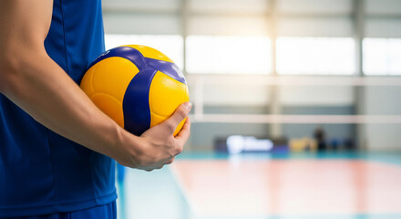 Male volleyball player holding a ball on an indoor court, ready to serve or play