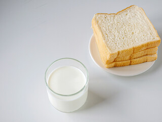 breakfast,Fresh milk in a glass and White sliced bread stacked on the white wooden table