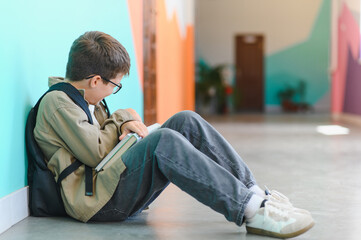 Sad schoolboy crying and holding books after bullying in school corridor