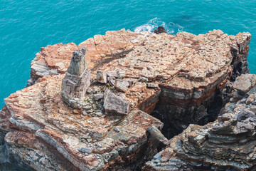 A stunning rocky cliff formation rising against the background of the blue ocean