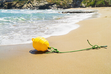 Yellow buoy washed ashore near the calm beach highlighting marine weather challenges