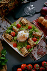 A Gourmet Presentation of Grilled Eggplant Rolls Stuffed with Cheese Served on a Bed of Fresh Greens and Cherry Tomatoes with a Touch of Cream