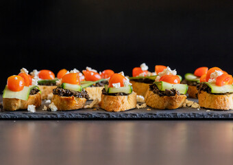 greek crostini with olive paste cucumber tomato and feta close up