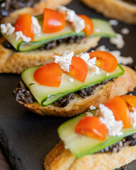 greek crostini with olive paste cucumber tomato and feta close up