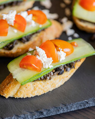 greek crostini with olive paste cucumber tomato and feta close up