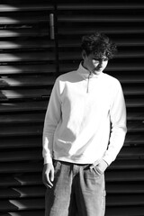 Style portrait of male model with beautiful eyes and hair in white sweater. Black and White. City urban architecture
