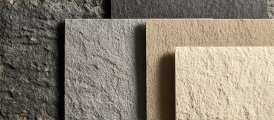 Textured tiles of varying shades, from dark gray to light beige, stacked