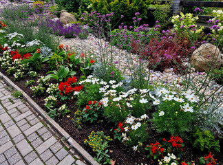 Fototapeta premium A colorful flowerbed with blooming annuals and a few stones and pebbles creating an optimistic meadow-like entrance to a spa hotel