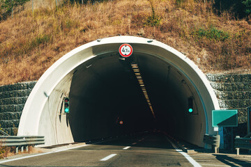 Modern road tunnel entrance in a dry mountain region with green traffic lights and height limit...