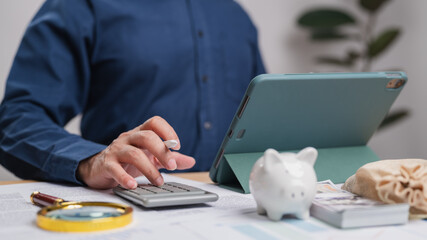 Businessman is calculating expenses, managing his budget savings investment. His desk has...