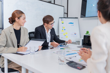 Group of Asian businesspeople sits down for a business investment planning meeting.	