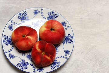 Peaches in a blue plate on a white background. Copy space.