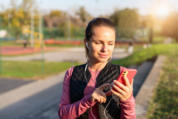 Active woman using fitness tracking app with headphones on mobile device
