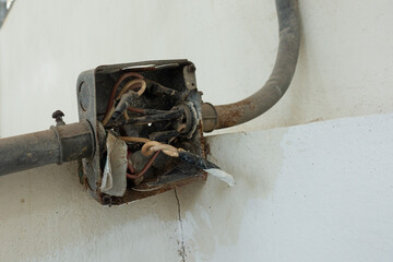 Old rusty electrical junction box on a concrete wall, The box is open and has several exposed...