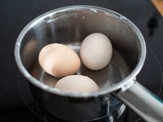 Boiled eggs in their shells in pot on electric stove
