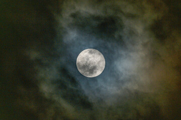 full moon in the midnight behind the cloudy sky
