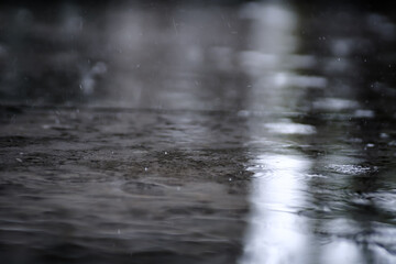 raining on the concrete walk way full with rain droplets splash ring bounce off the surface of water with reflected of white cloudy sky
