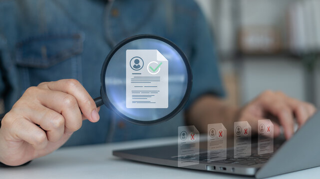 Close-up of a magnifying glass highlighting a selected resume on a laptop with rejected CVs in the background. Concept of digital recruitment, candidate screening, and hiring process.